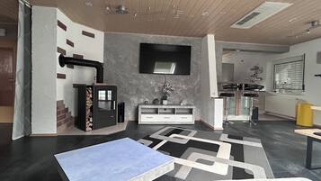 A modern living room with a fireplace, a flat-screen TV, and a dining area with a bar.