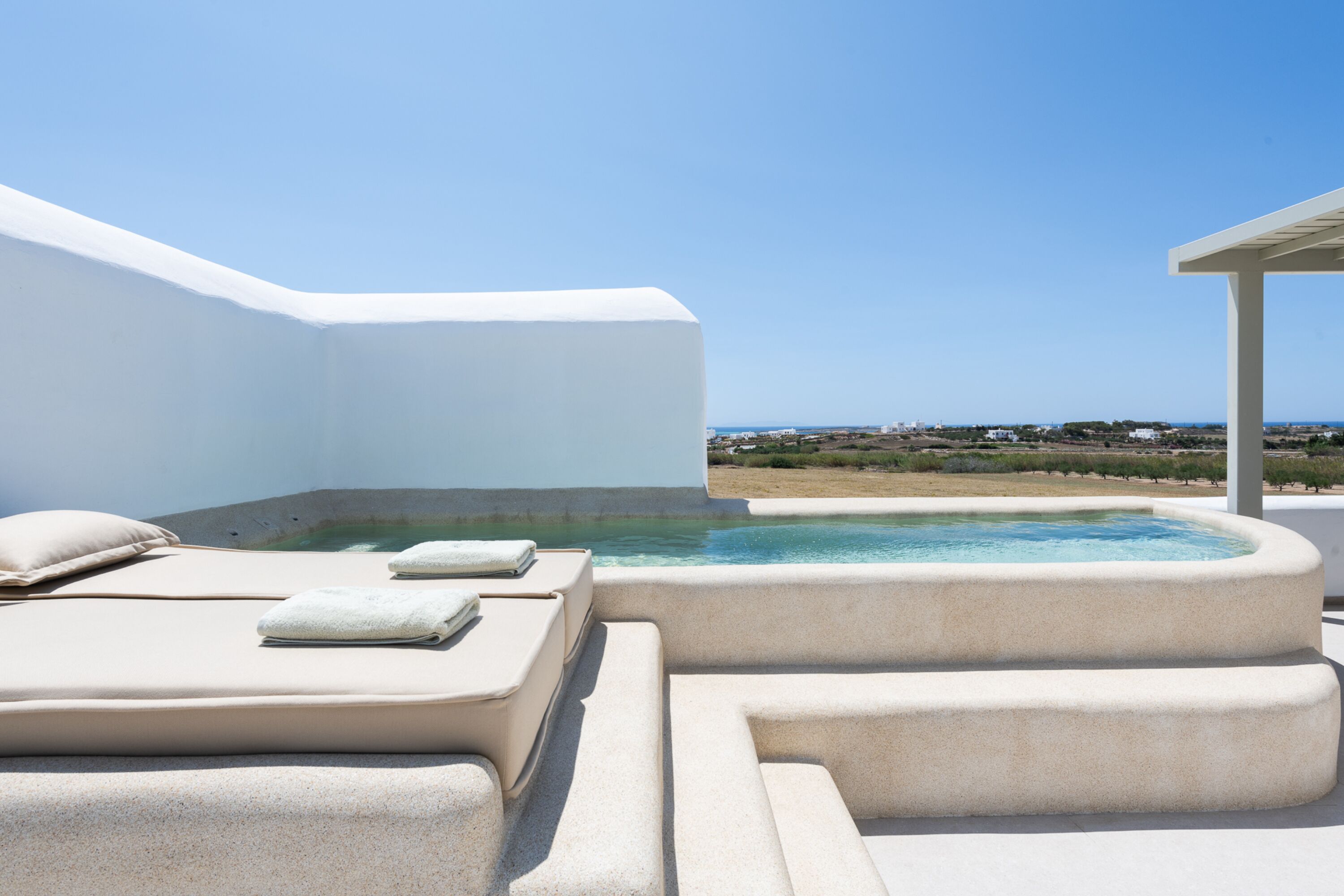 A spa area with a hot tub and lounge chairs, overlooking a coastal landscape.