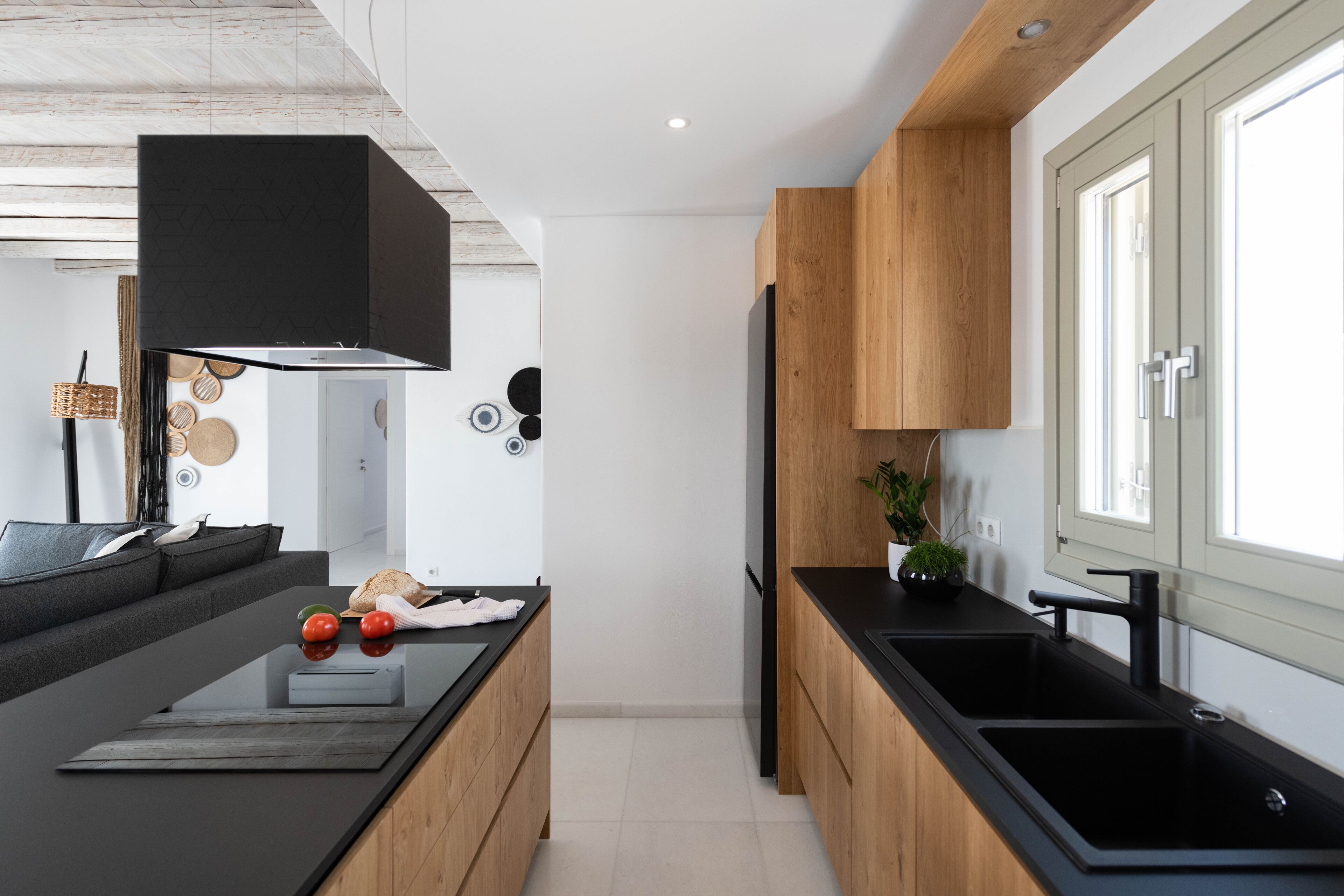 Cocina moderna con armarios de madera, encimeras negras y una isla central con lavamanos.