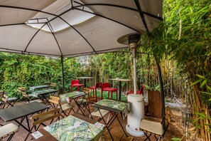 An outdoor patio with tables and chairs, surrounded by lush greenery. - Hostel e Cia Porto (Porto)