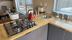 A modern kitchen with a gas stove, kettle, toaster, and stainless steel sink. - 2-bed House in Dullstroom , Blue Crane Estate 66 (Dullstroom)