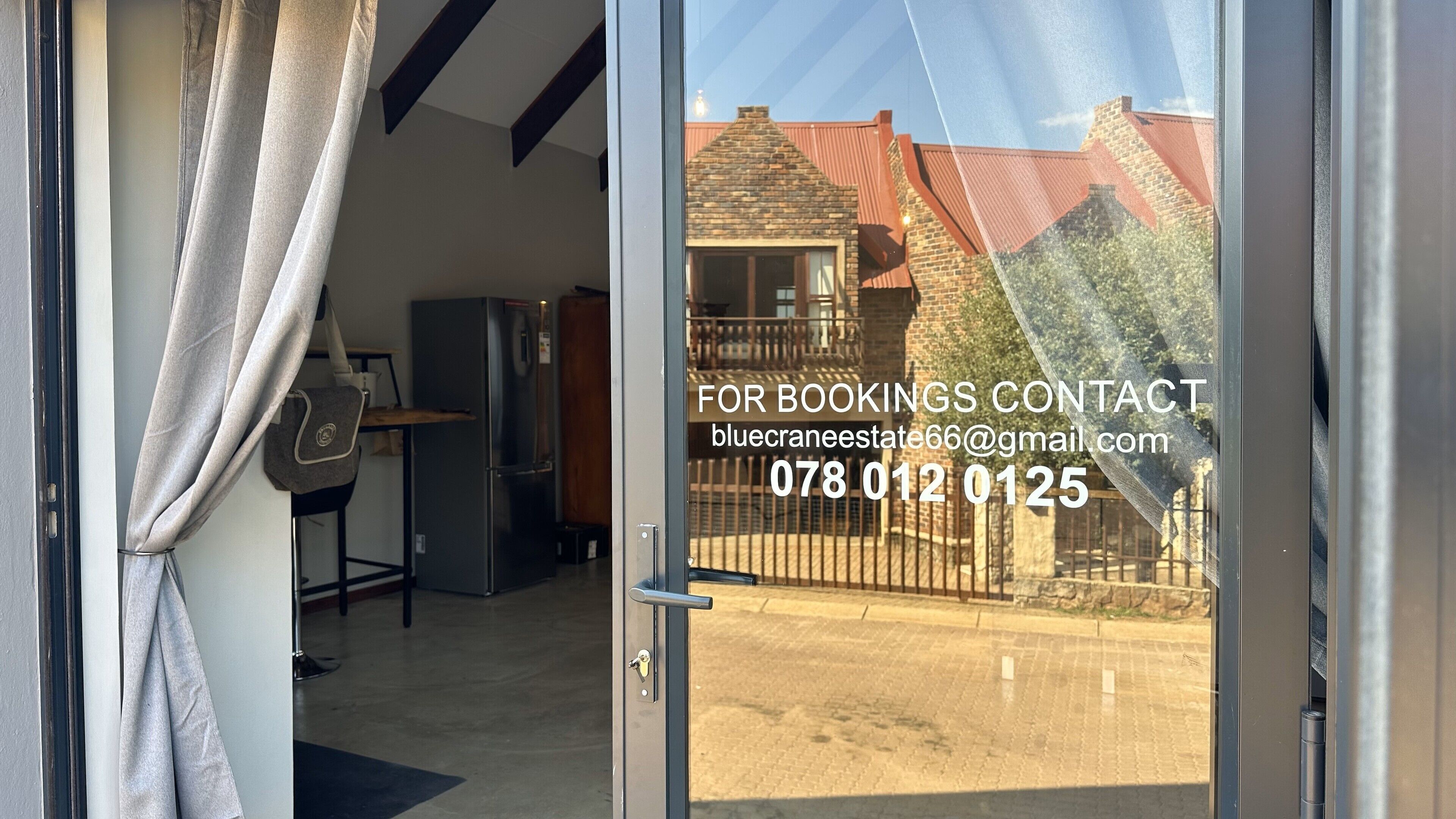 A glass door with a contact email and phone number for bookings.