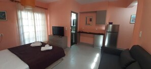 Een hotelkamer met een bed, een televisie, een kitchenette en een koelkast.