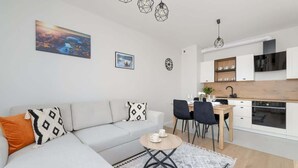 Ein modernes Wohnzimmer mit einer Couch, einem kleinen runden Tisch und einer Küchenzeile mit Schränken und einem Esstisch.