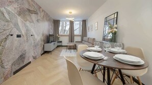 Un comedor moderno con pared de mármol, una mesa de comedor con platos y vasos, y un sofá al fondo.