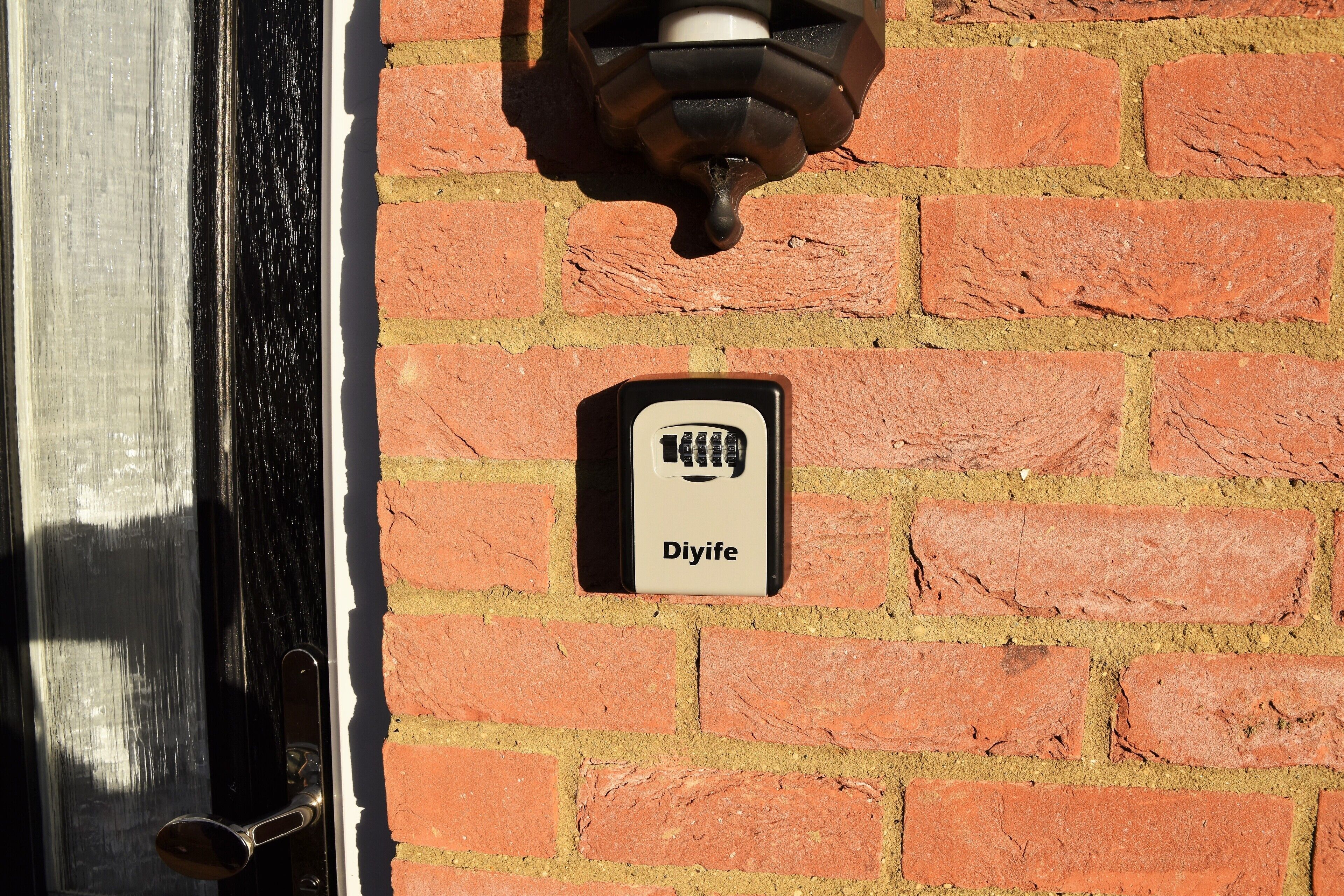 Una puerta con un picaporte negro y una pared de ladrillo con un letrero de 'Diyife'.
