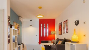 A modern living room with a red accent wall, a sofa, a coffee table, and a laptop.