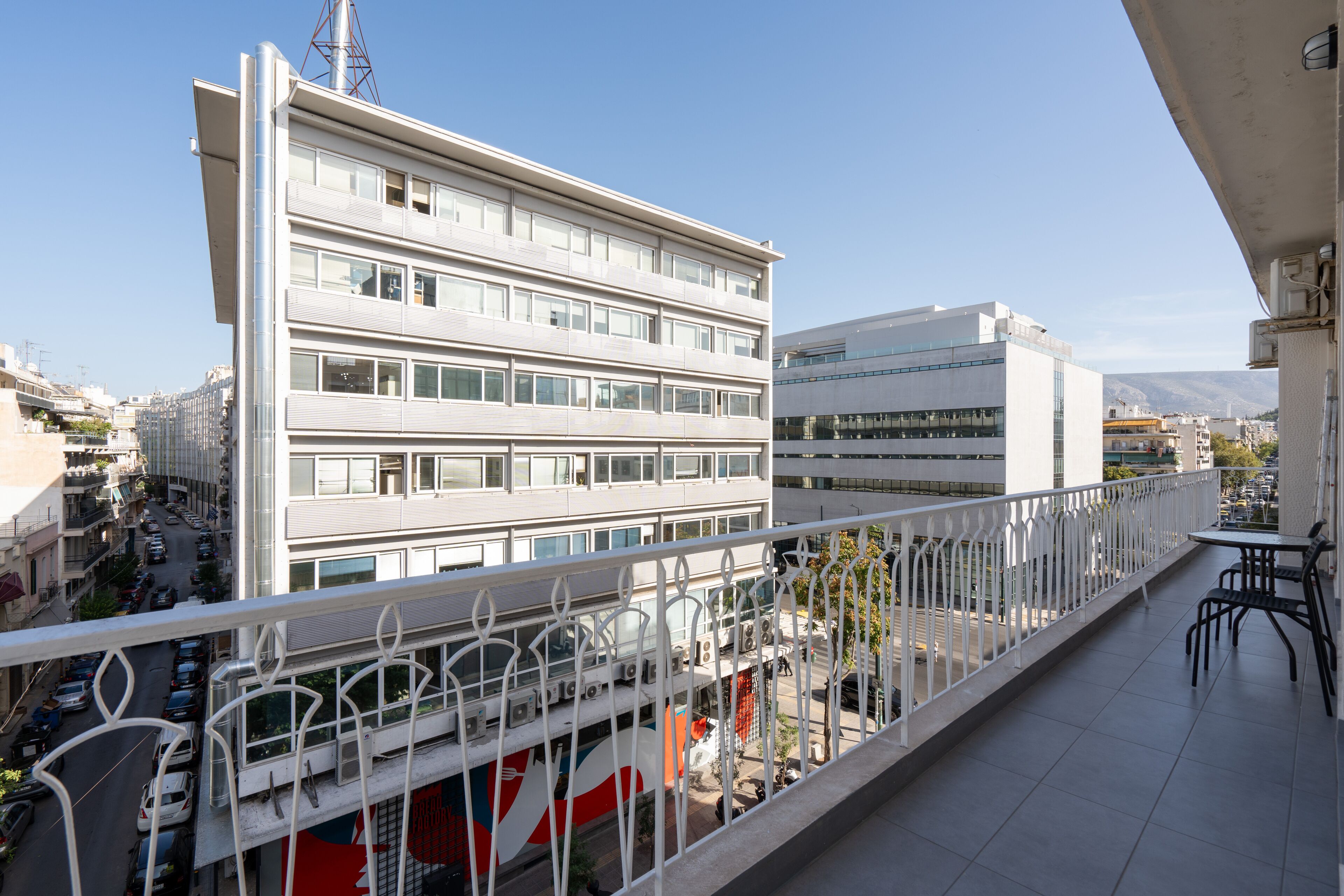 A modern building with multiple floors, a balcony with a railing, and a view of a busy street below.