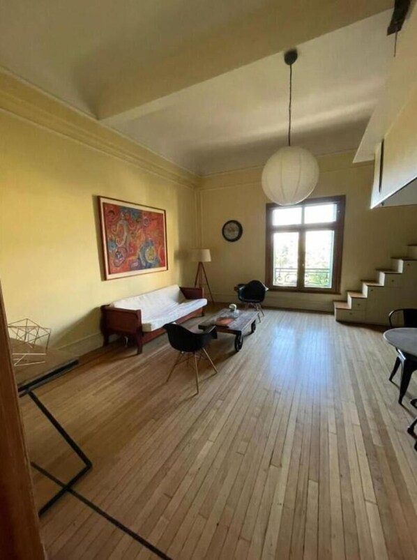A spacious living room with a wooden floor, a sofa, a coffee table, and a painting on the wall. - Loft en Casco Histórico de Santiago (Santiago)