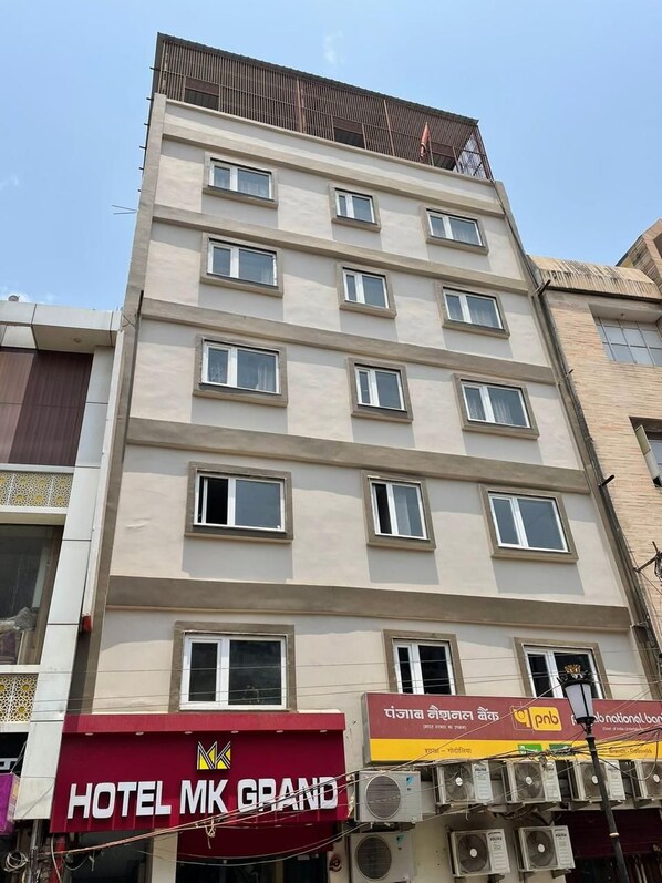 A multi-story building with a sign for "HOTEL MK GRAND" at the ground level. - Hotel M K Grand (Varanasi)