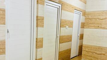 Un pasillo con tres puertas blancas, cada una con pomo, en una pared con un diseño parecido al mármol. El suelo está cubierto de baldosas con un patrón similar.