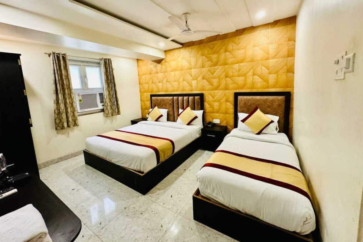 Una habitación de hotel con dos camas, un ventilador de techo, una ventana con cortinas y una pared con un diseño geométrico.