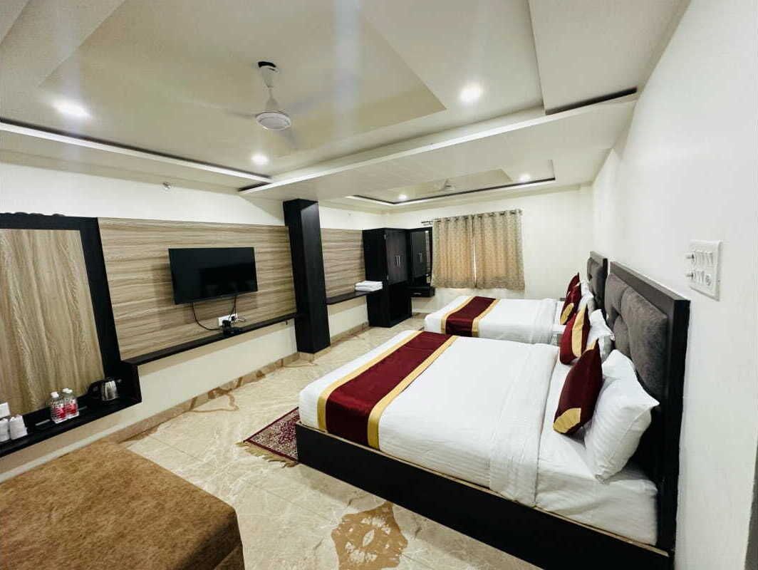 Habitación de hotel con dos camas, un televisor de pantalla plana, ventilador de techo y minibar.