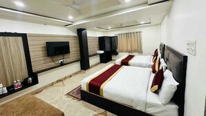 Habitación de hotel con dos camas, un televisor de pantalla plana, ventilador de techo y minibar.