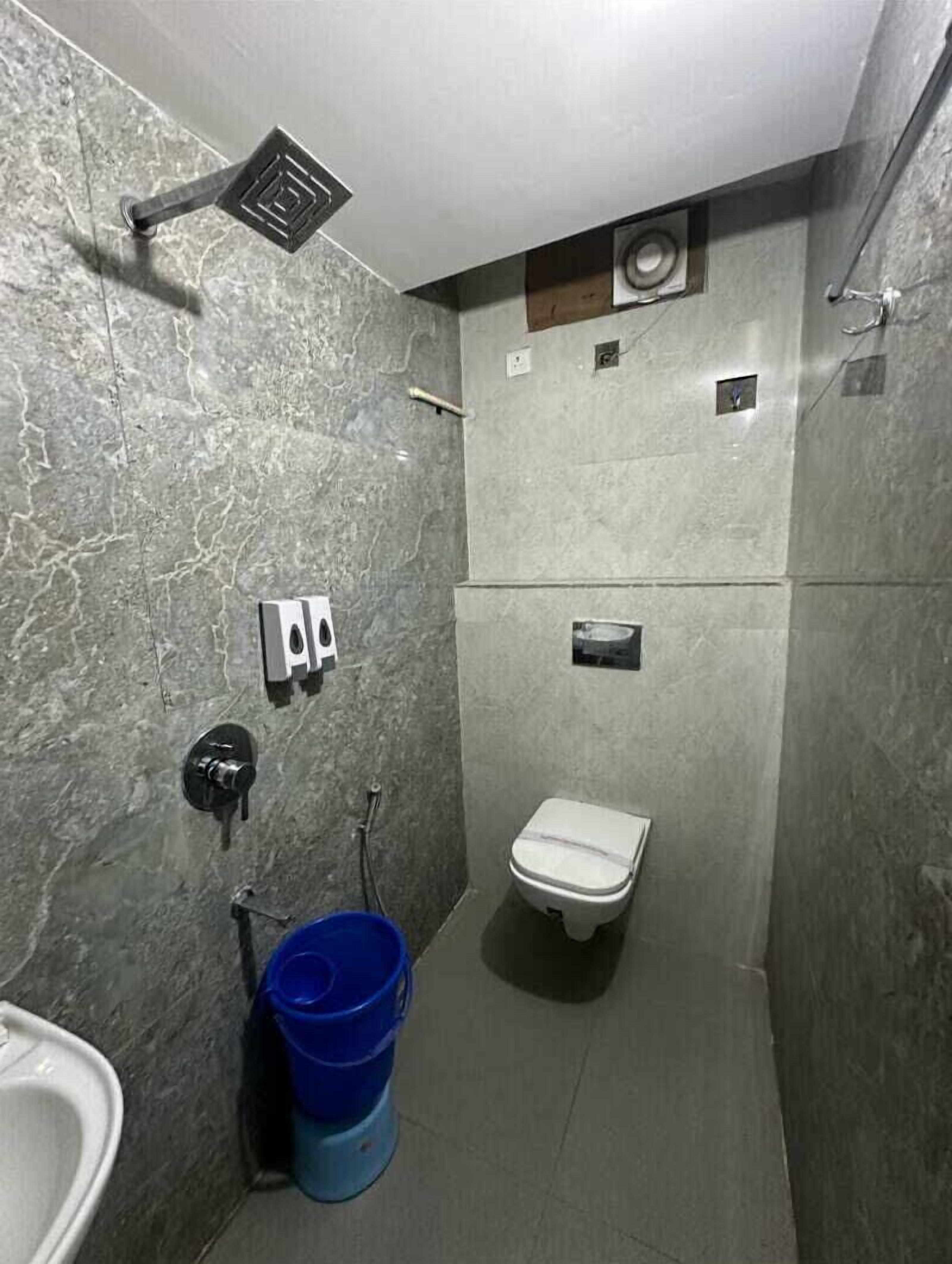 A small, compact bathroom with a toilet, a wall-mounted sink, and a showerhead.