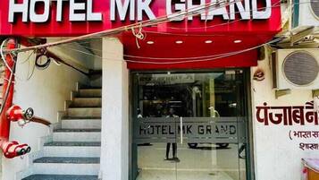 Entrada de hotel con toldo rojo y un letrero que dice "HOTEL MK GRAND".