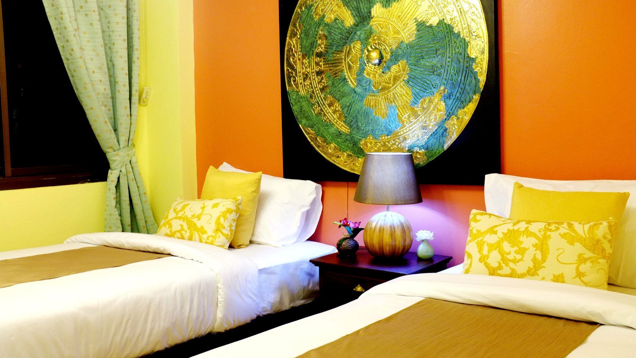 Une chambre d’hôtel avec deux lits, une œuvre d’art représentant un globe terrestre accrochée au mur et une lampe sur une table de chevet.