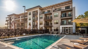 A modern multi-story building with a swimming pool and outdoor seating area. - Cozysuites Stylish 4BR the heart of Nora (Indianapolis)