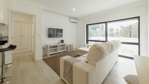 A modern living room with a sofa, a TV, and a large window. - Pateo IN Lapa City Center by Vacationy (Porto)