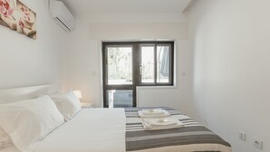 A hotel room with a bed, a window, and an air conditioning unit. - Pateo IN Lapa City Center by Vacationy (Porto)