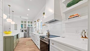 A modern kitchen with white cabinetry, stainless steel appliances, and pendant lighting. - Sea Pearl- Jewel of Gulf Shores! Community pool (Gulf Shores)