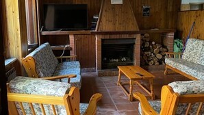 A cozy living room with wooden furniture, a fireplace, and a television. - 2 Bedroom Apartment in Celico (Celico)