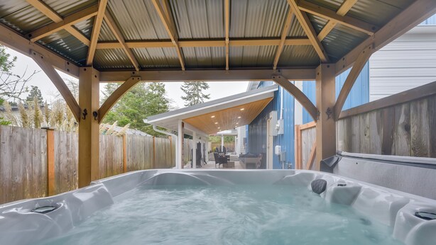 A hot tub under a wooden pergola with a view of a house in the background. - Westport Home w/ Hot Tub: 2 Blocks to Beach! (Westport)