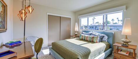 A bedroom with a bed, bedside tables, a desk, and a chair.