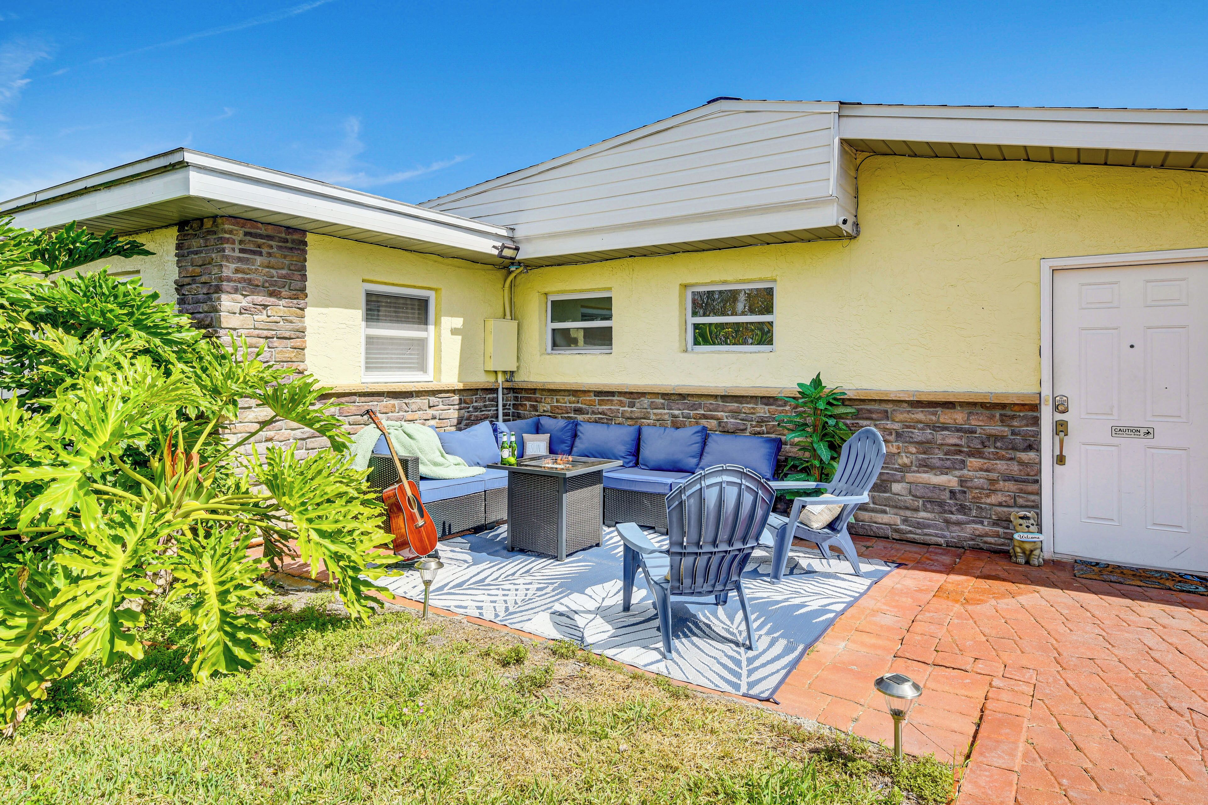 A patio with outdoor furniture, a stone wall, and a door with a caution sign.