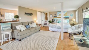 A well-lit living room with a sofa, a coffee table, and a TV. There is a staircase leading to another room. - Waterfront Daytona Escape w/ Pool & Game Room! (Daytona Beach)