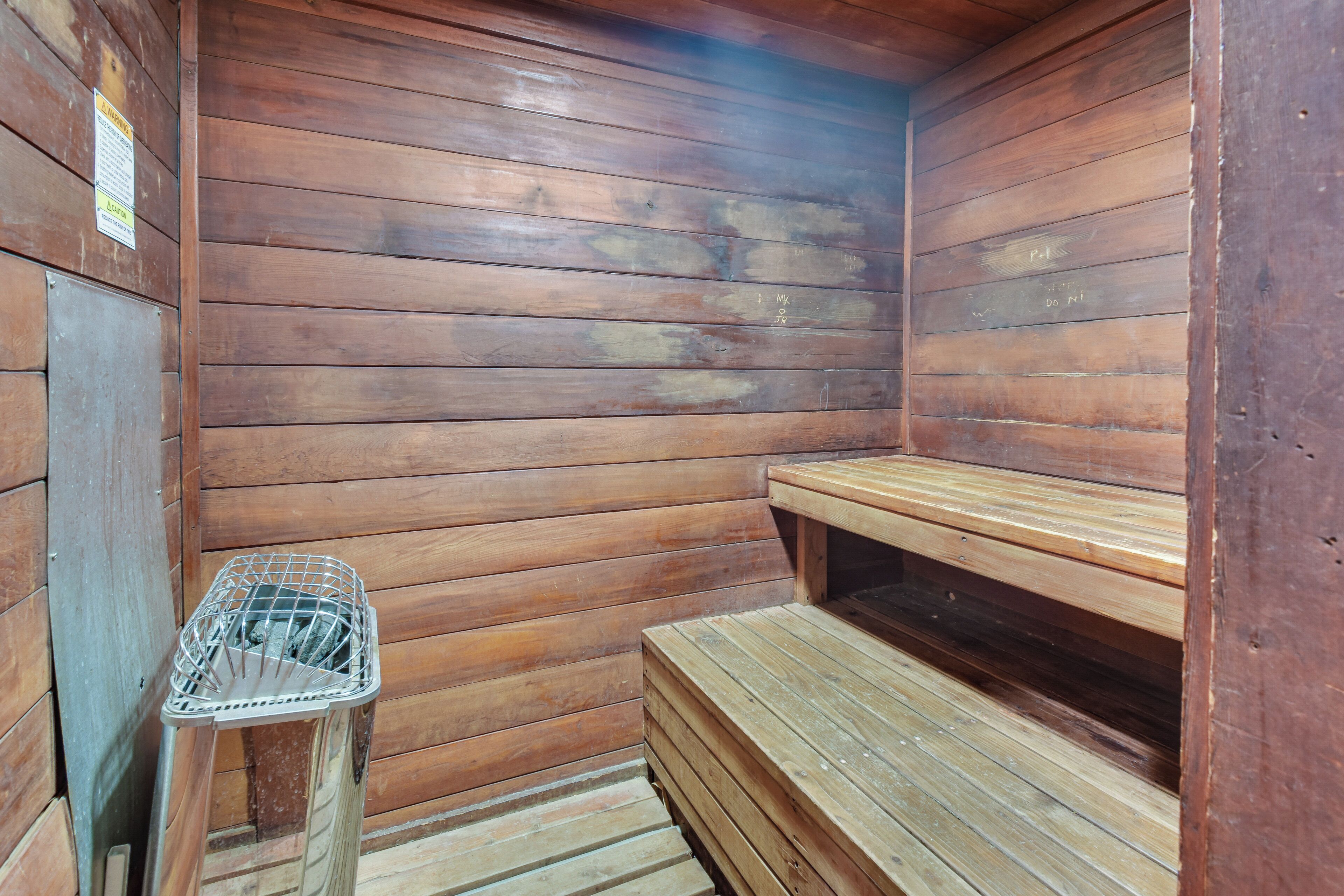Een houten sauna met banken en een metalen mand.
