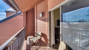 A balcony with a chair and a small table, a sliding glass door, and a view of the outside. - Steamboat Springs Condo: Community Pool & Hot Tub! (Steamboat Springs)