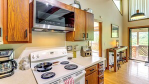 A kitchen with wooden cabinets, a microwave, a stove, and a coffee maker. - Maggie Valley Mountain Escape w/ Fireplace & Deck! (Maggie Valley)