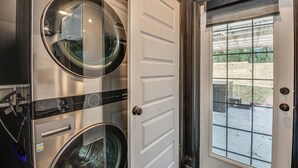 Ein Waschraum mit zwei übereinander gestapelten Frontlader-Waschmaschinen und einer Tür zu einem Außenbereich.