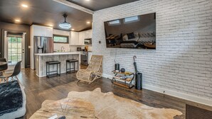 Eine moderne Küche mit weißen Schränken, einer Bar und einem Essbereich mit einer Ledersofa und einem Holztisch.