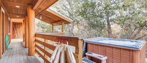 A wooden deck with a hot tub, wooden benches, and a wooden structure with a ladder.