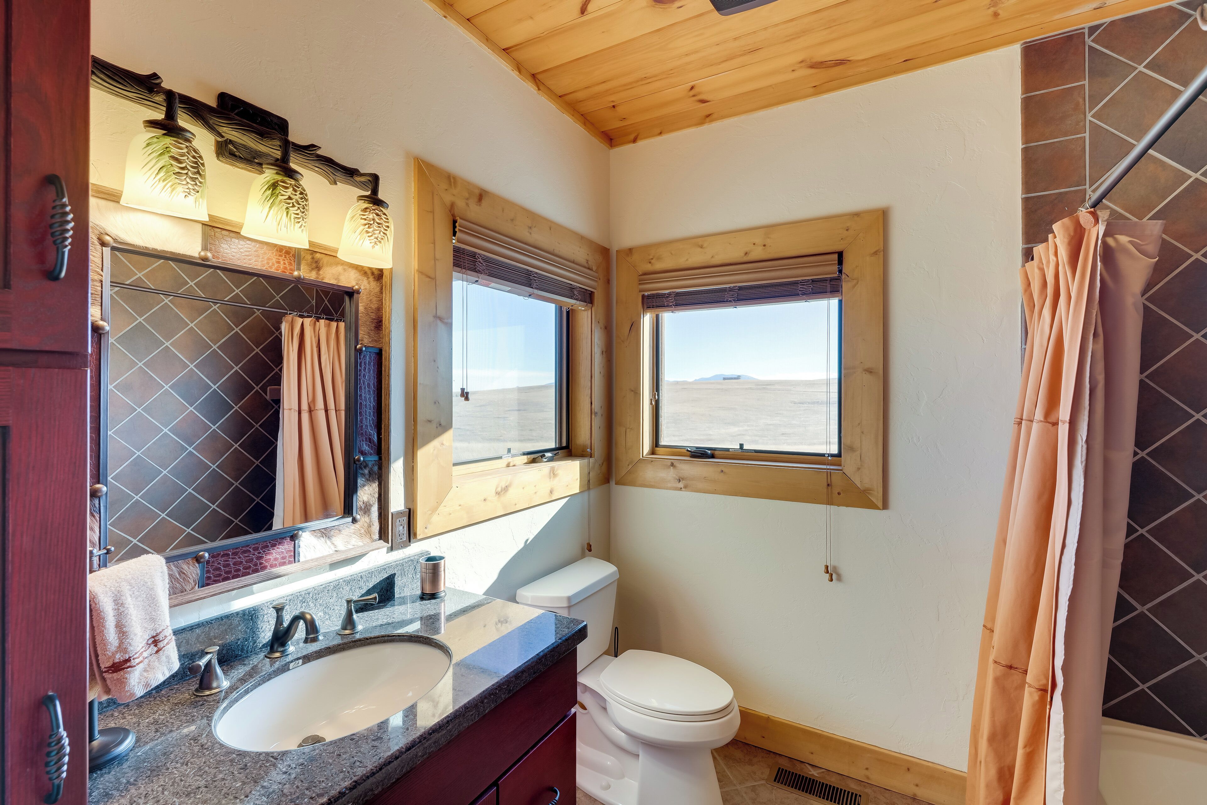 A bathroom with a large window, a sink, and a toilet.