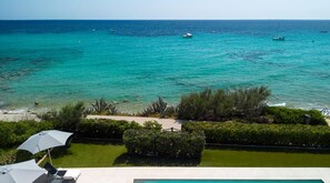 A view of a pool area with a clear blue sea in the background, surrounded by greenery and a few boats. - Villa Ponti A5 Frontline by Book Menorca Villas (Urbanització Santo Tomàs, Es Migjorn Gran)