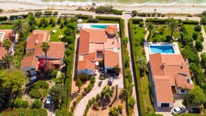 An aerial view of a coastal residential area with houses, a swimming pool, and a beach.