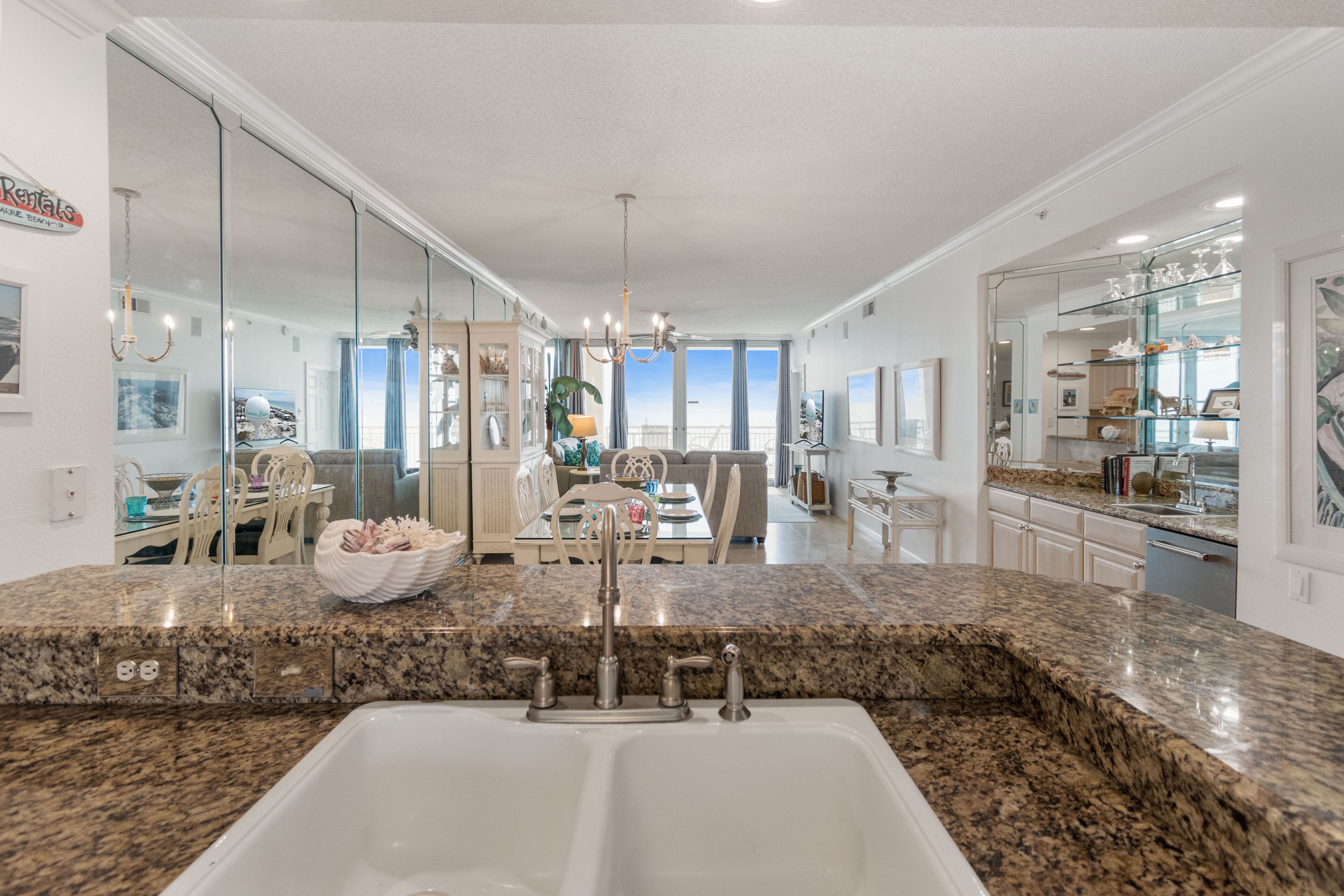 A modern kitchen with granite countertops, a double sink, and a dining area with a view.