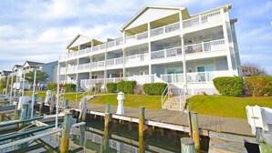 A multi-story hotel with balconies, a dock, and a grassy area. - Baywatch Iii 302a 2 Bedroom Condo by RedAwning (Ocean City)