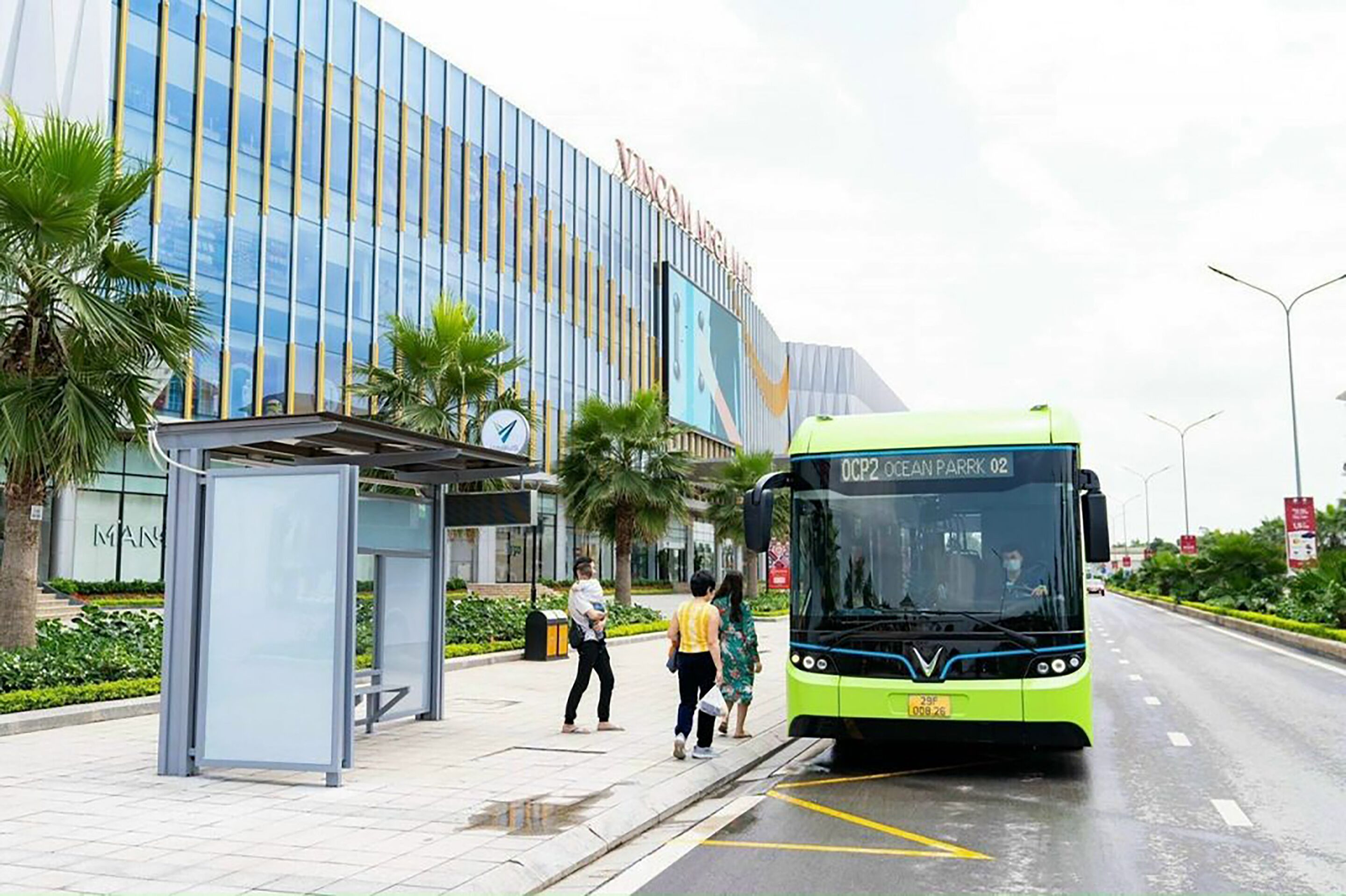 A modern building with a glass facade and a bus stop in front.