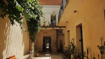 A narrow courtyard with a spiral staircase, potted plants, and a bicycle.