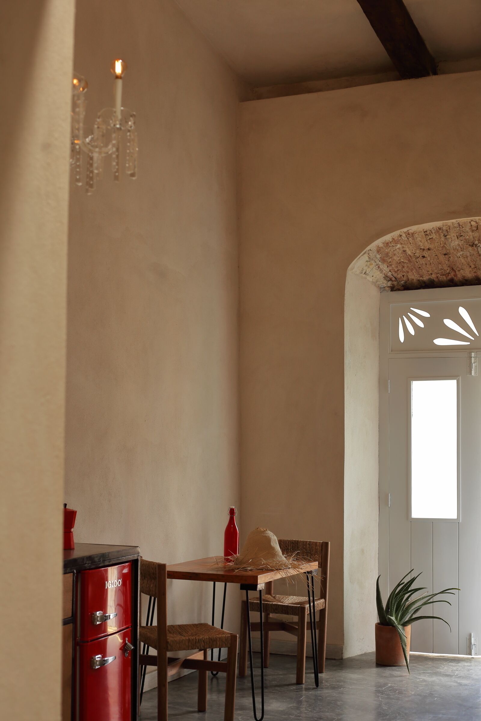 A dining area with a wooden table and chairs, a red cabinet, and a potted plant.
