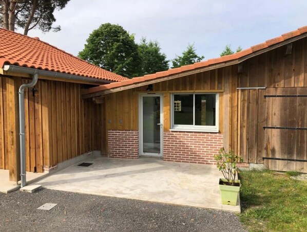 Cozy single-story home with a sloped roof and brick foundation, featuring a welcoming entryway with a glass door.