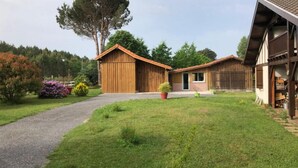 A two-story wooden house with a sloped roof, a paved driveway, and a well-maintained lawn.