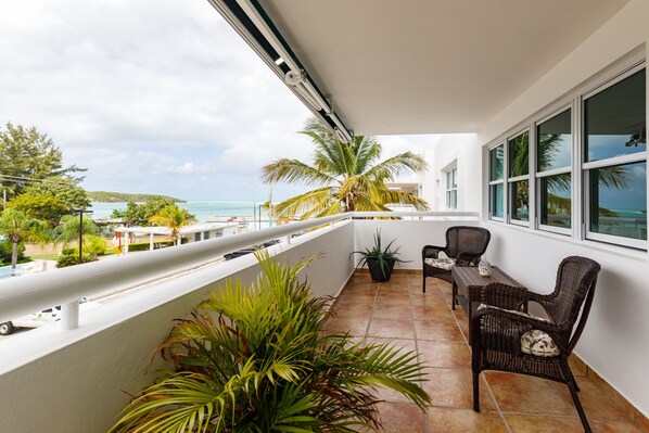 Ein Balkon mit Meerblick, zwei Korbstühle und ein Blumentopf.