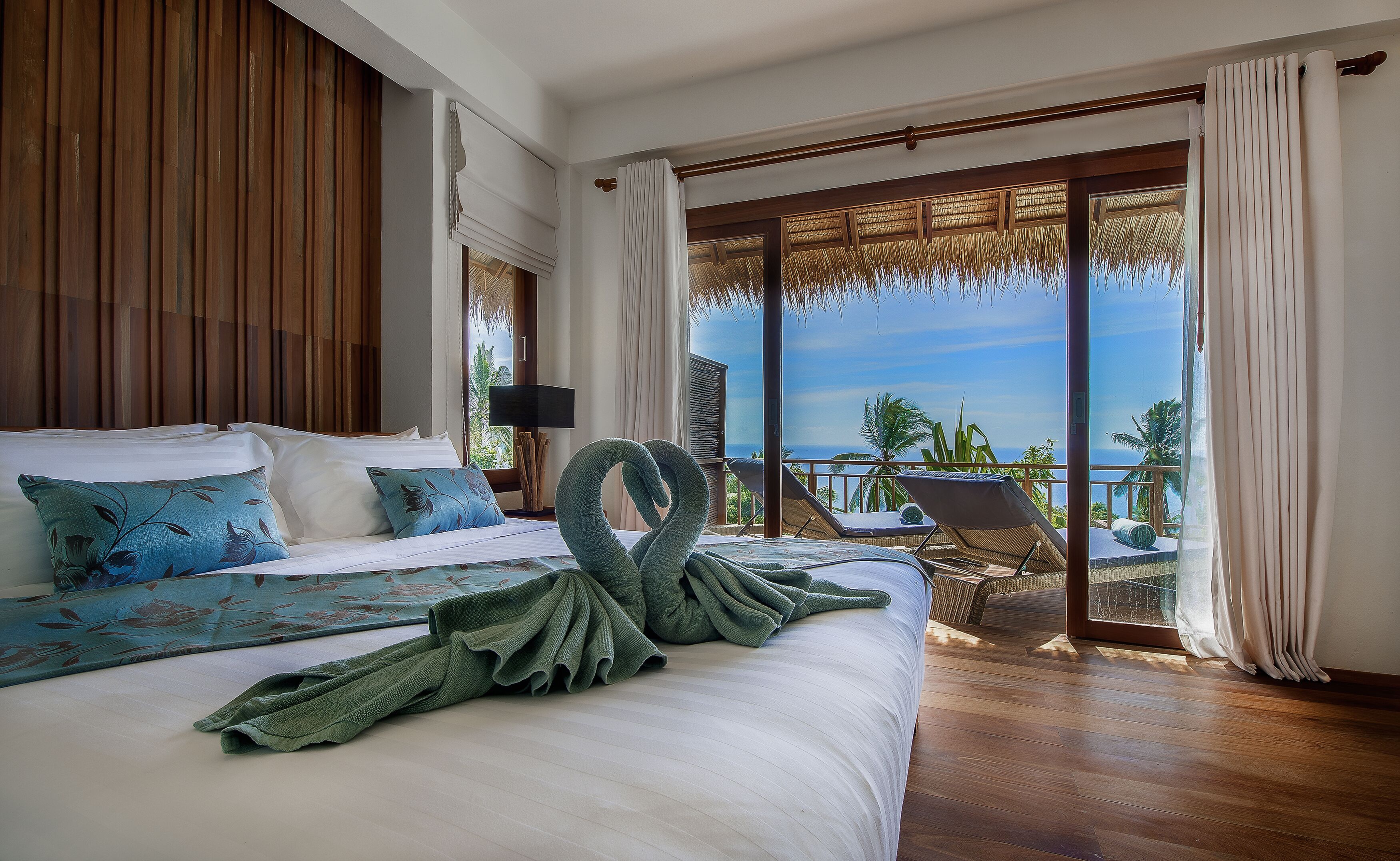 Une chambre d’hôtel avec un lit, une vue sur l’océan et un balcon équipé d’une chaise.