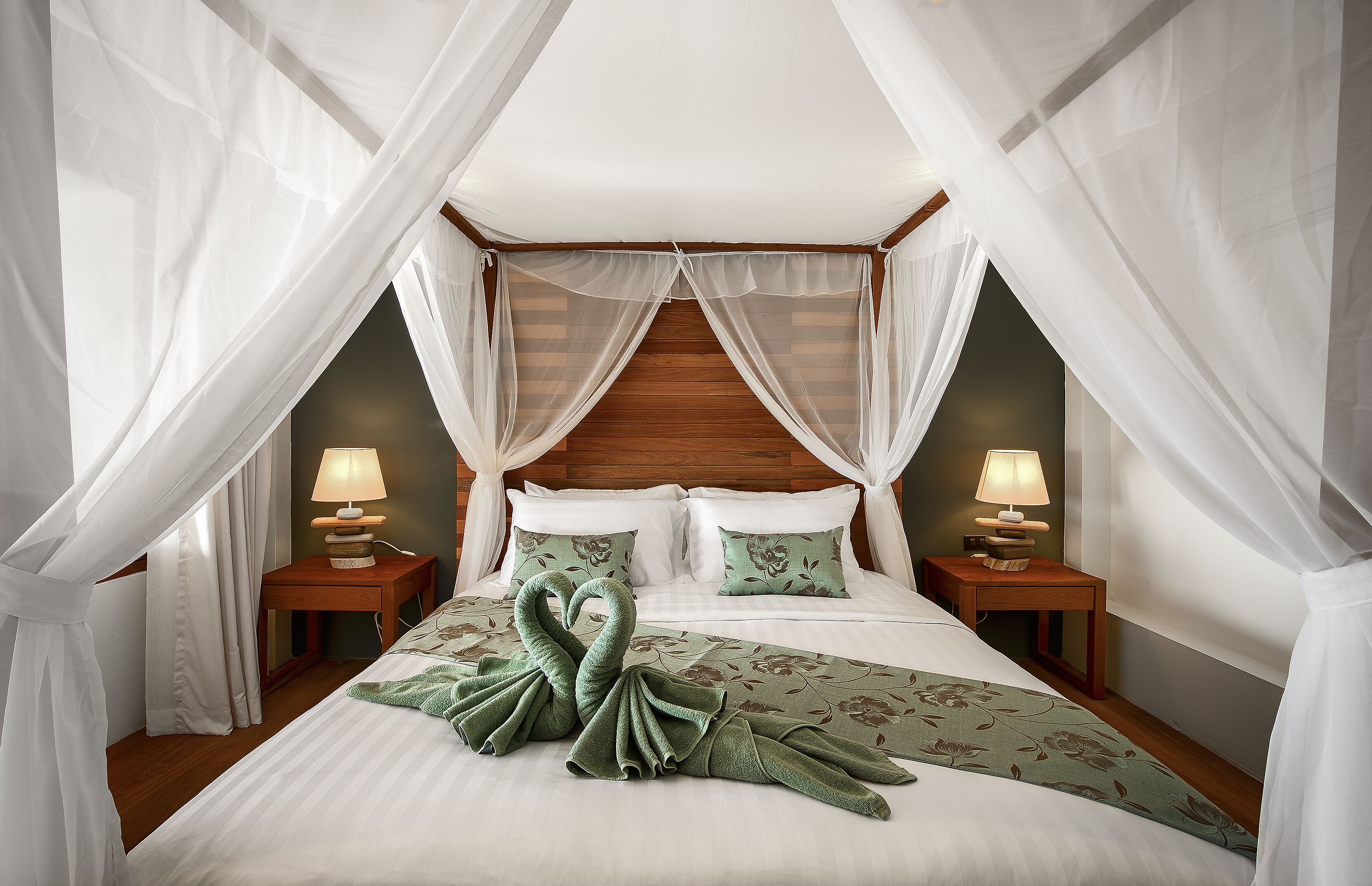 Une chambre à coucher avec un lit à baldaquin, deux lampes de chevet et une couvre-lit à motifs floraux.