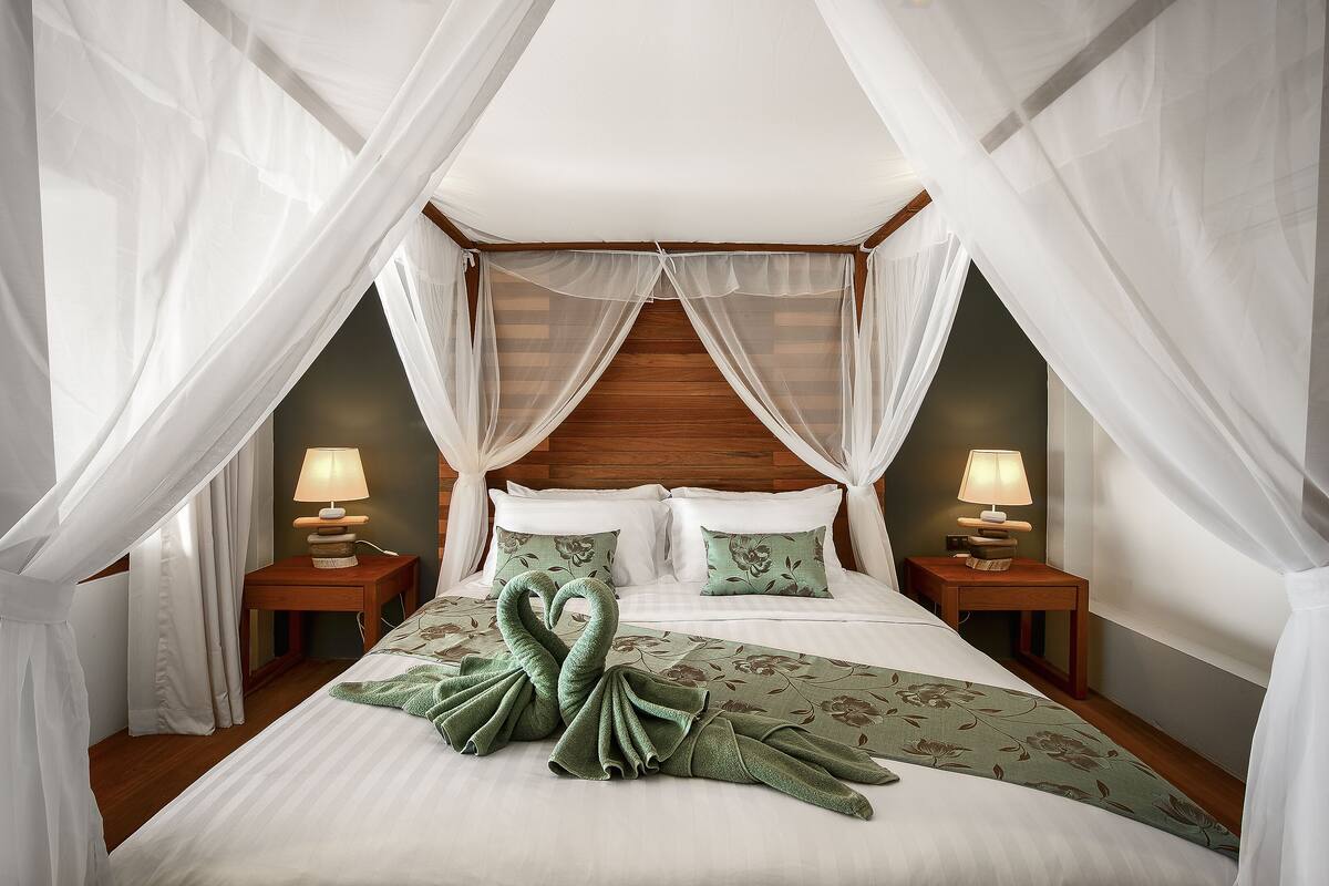 A bedroom with a canopy bed, two bedside lamps, and a floral bedspread.
